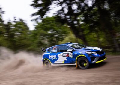 The driver of a Renault rally car expertly handles the steering wheel through a challenging section of the course.