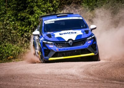 The driver of a Renault rally car expertly handles the steering wheel through a challenging section of the course.