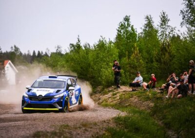 Renault rally car powerslides through a hairpin turn, demonstrating exceptional car control.